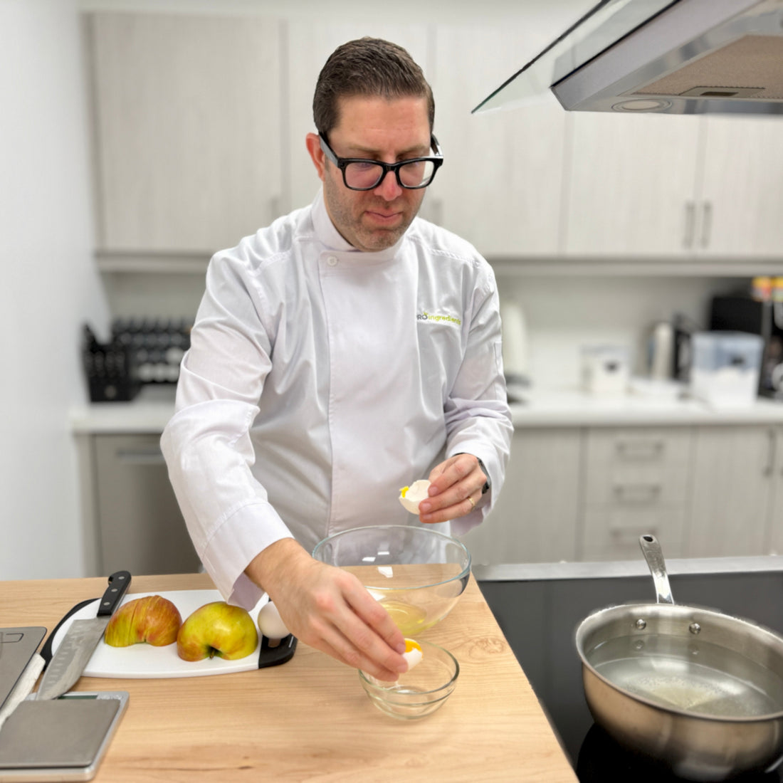 Person in a kitchen preparing food, wearing a white chef's coat.
